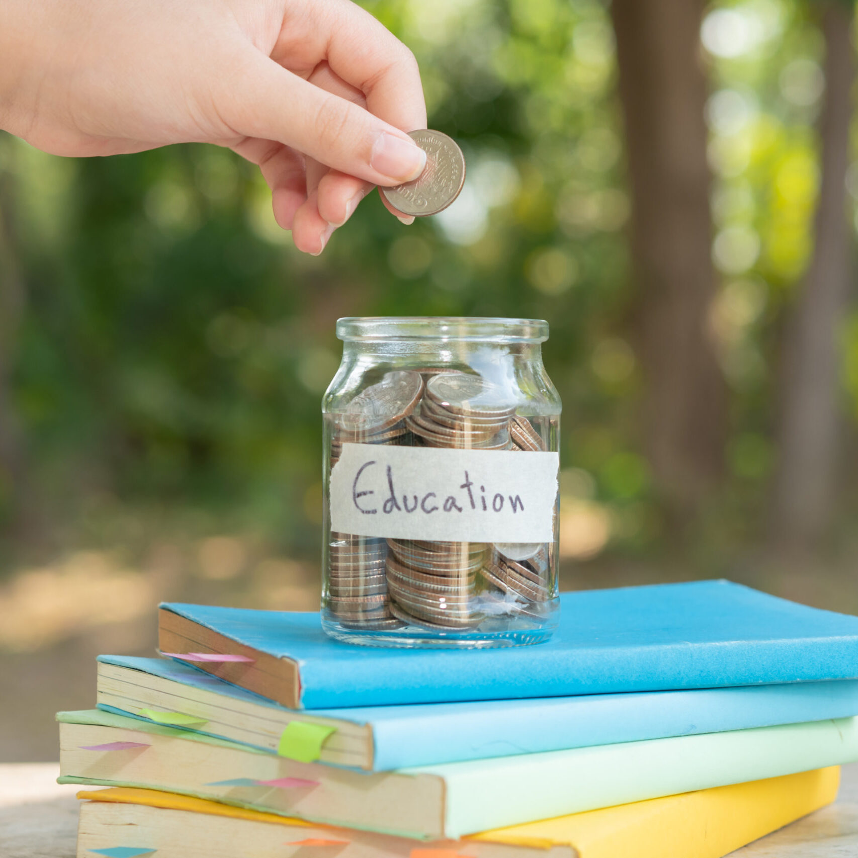 putting money coins saving in glass bottle for concept investment mutual fund finance and business, placed on the textbook. content money saving for education.