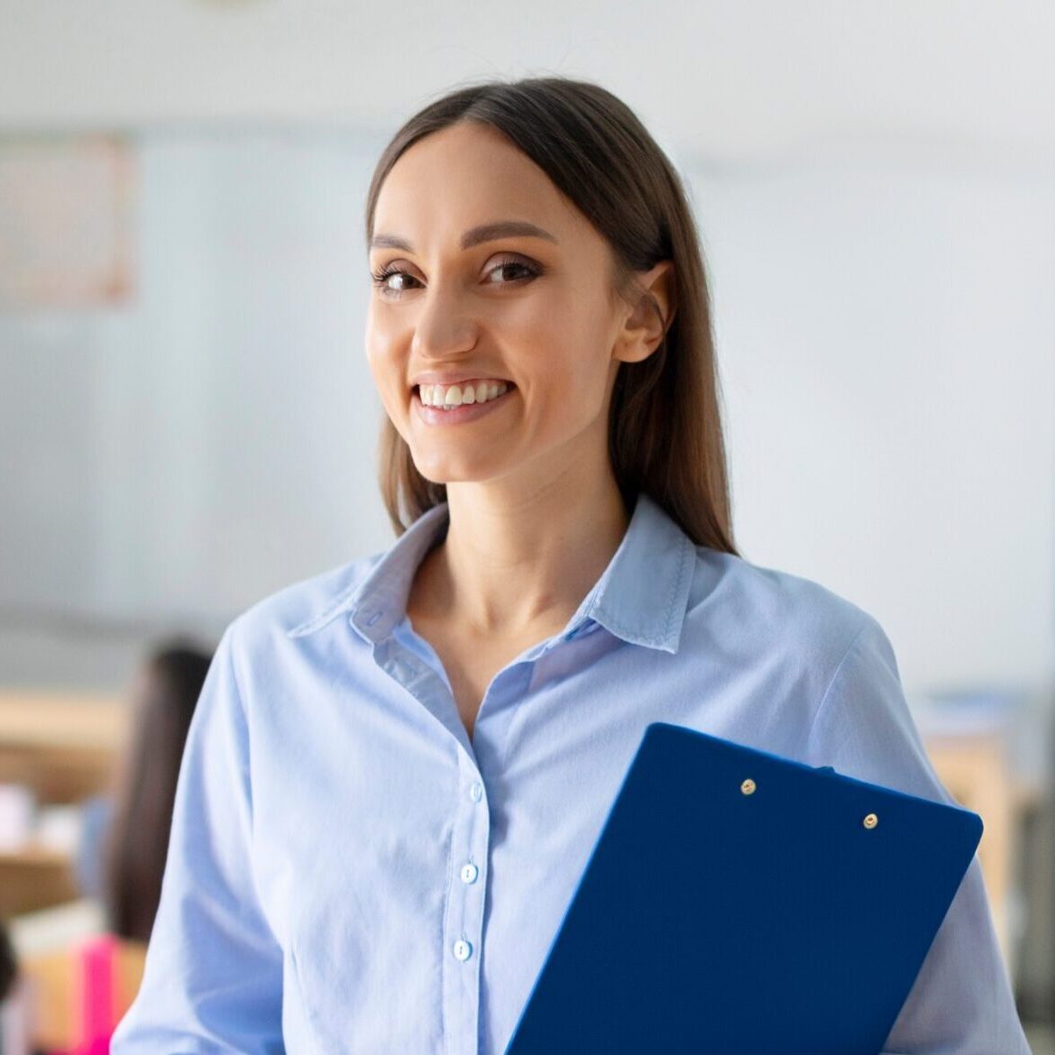 Portrait,Of,Cheerful,European,Female,Teacher,Standing,In,Classroom,During